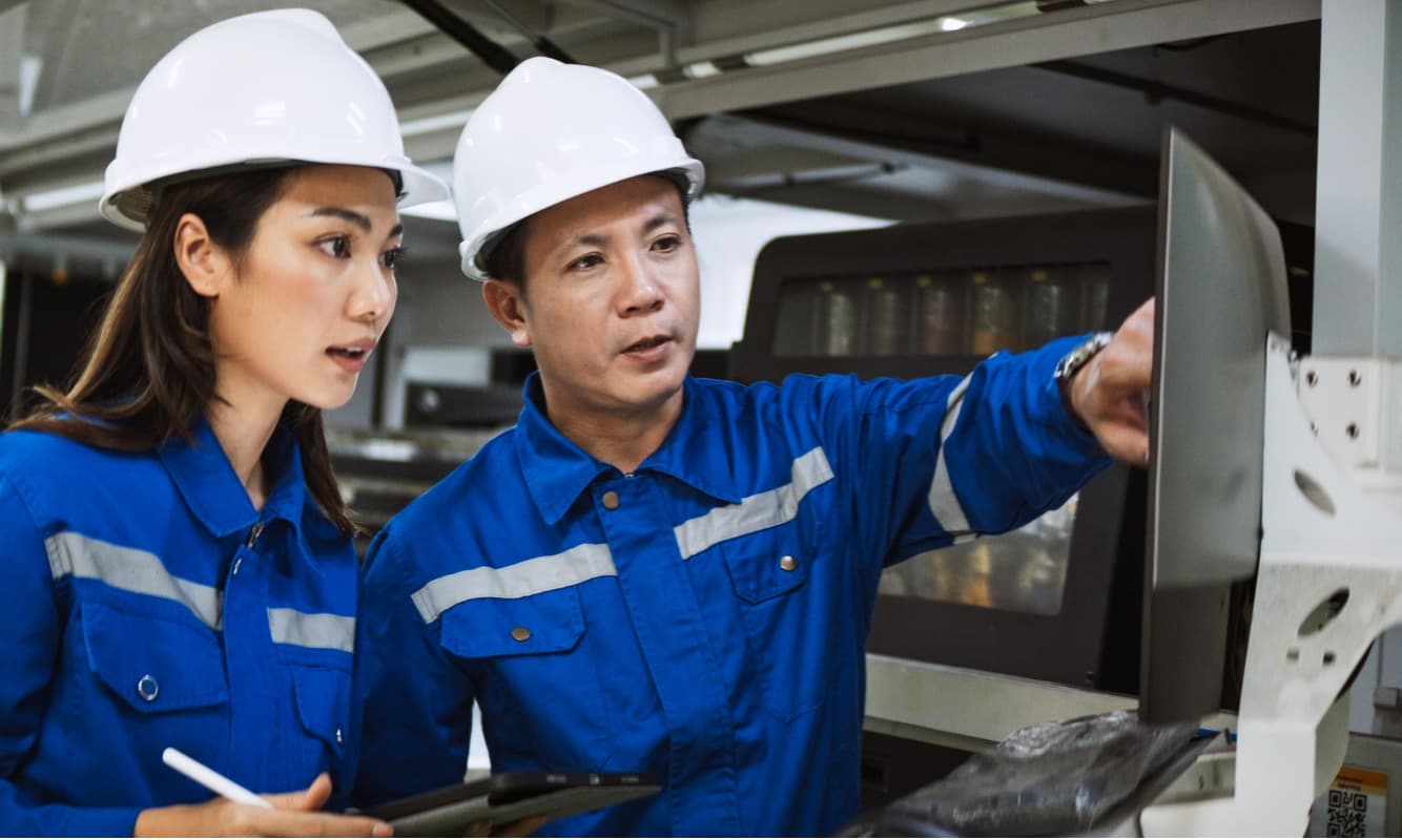 Manufacturing engineers discussing data insights from a computer.