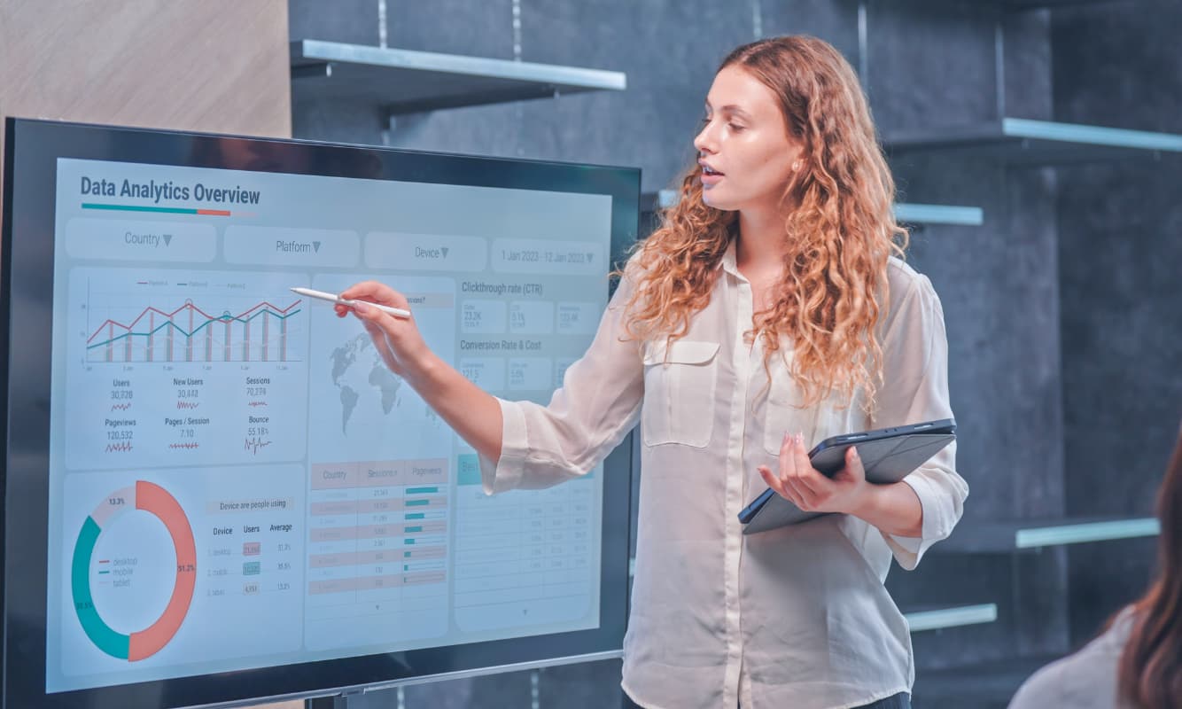 A business executive presenting a healthcare data analytics overview on a large screen.