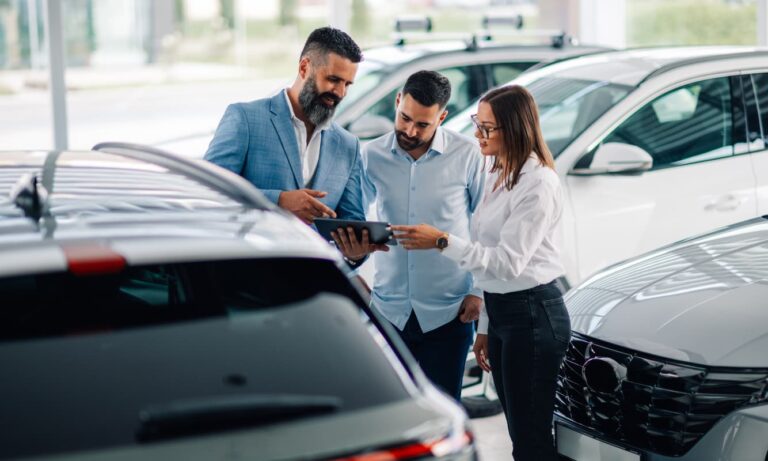 Automotive dealership representative talking to two customers at a showroom