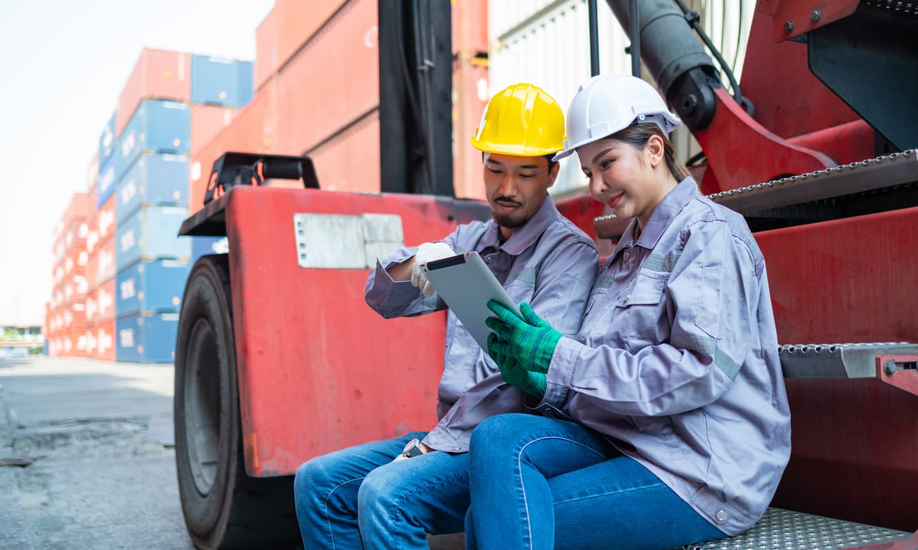 Two manufacturing engineers monitoring supply chain developments on a tablet.