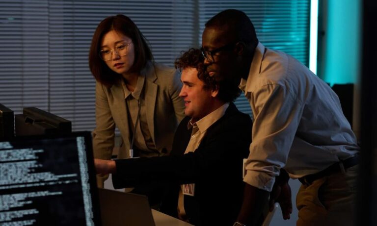 Three IT professionals discussing the benefits of observability and AIOps integration in front of a computer