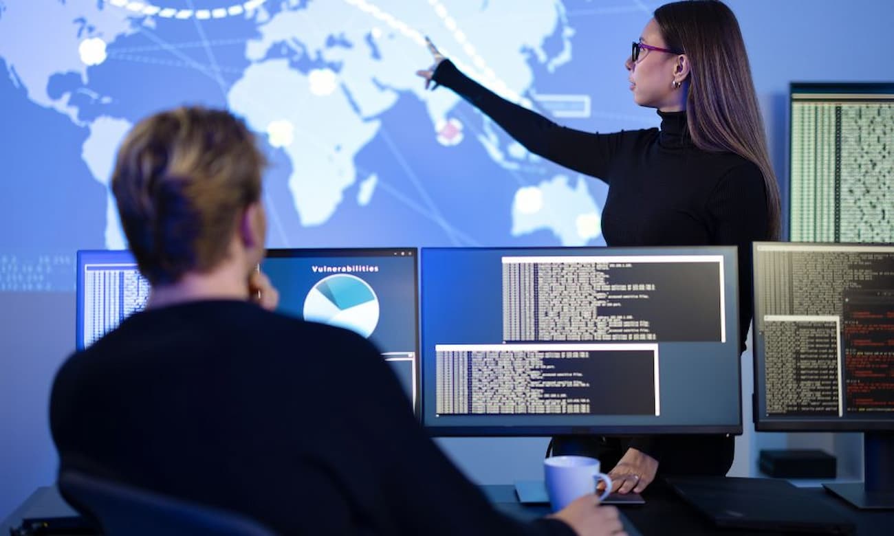 Professional IT team managing a domain and identity migration, resolving security and access issues, with a woman pointing to an event map.