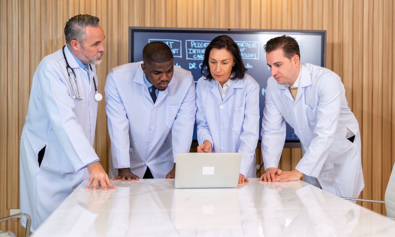 A Group of doctors looks at a medical report on a laptop computer
