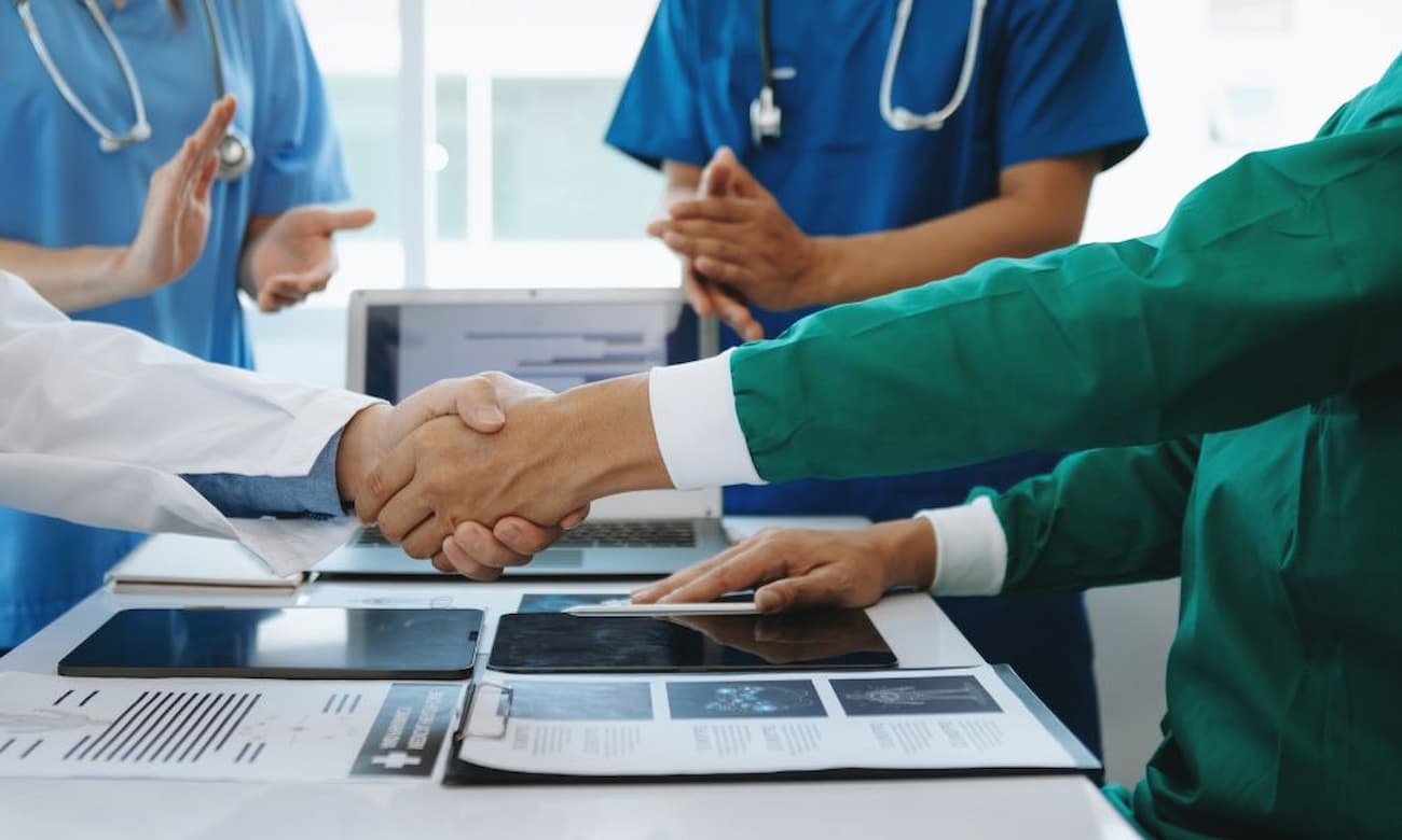 Two doctors shake hands to celebrate a successful healthcare merger