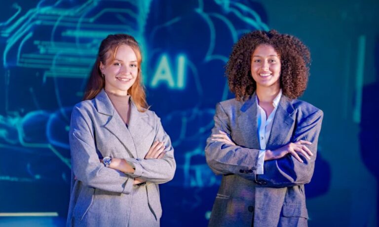 Two young women stand confidently in a modern workplace, arms crossed, against a vibrant blue backdrop featuring an 'AI' design.