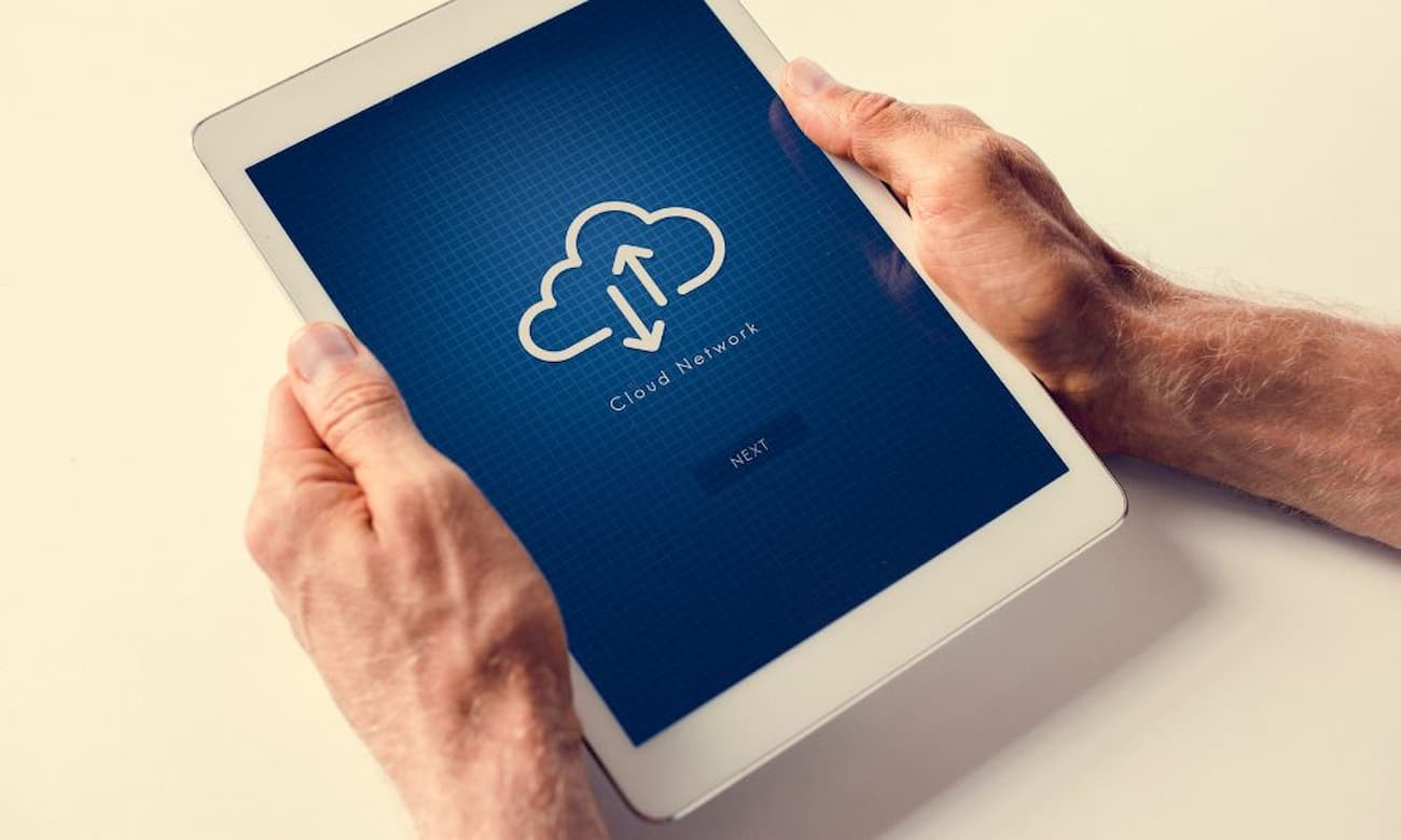IT expert holds tablet displaying cloud network graphic