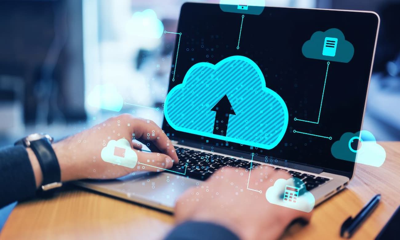 Expert typing on a laptop displaying a cloud graphic