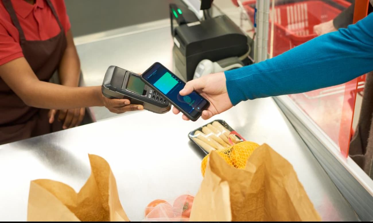 Customer completing a contactless payment at a supermarket checkout counter.